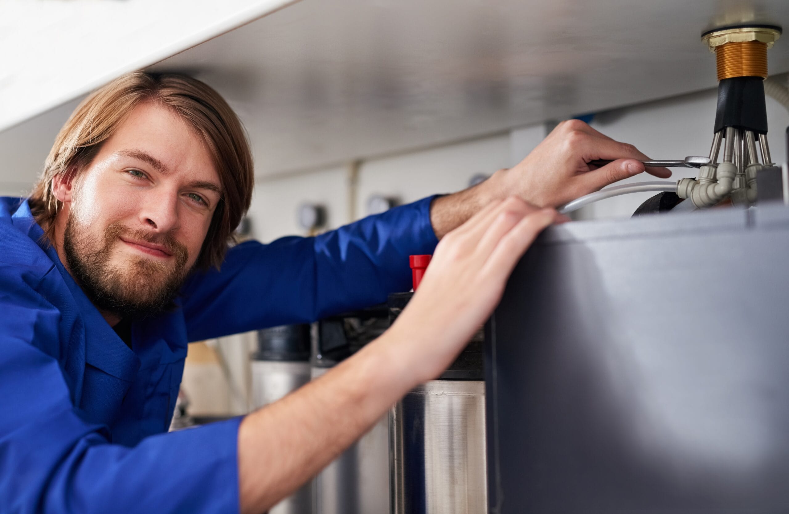 Technician servicing a residential water heater tank in San Rafael